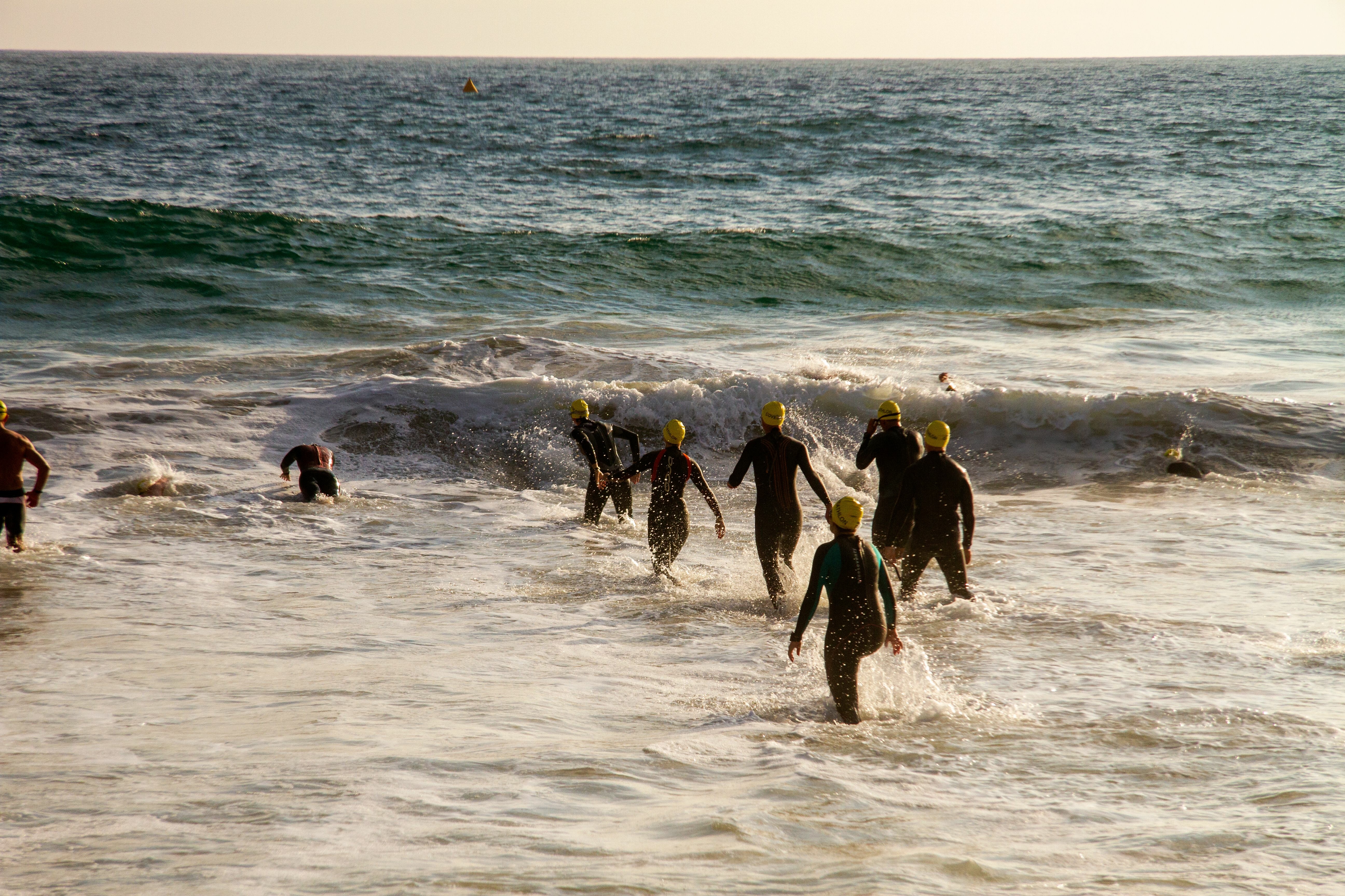 swimmers walking into the sea at sunset